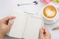 Woman hands holding notebook with pen and coffee cup on white wooden table. Royalty Free Stock Photo