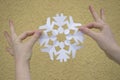 WOMAN HANDS HOLDING PAPER SNOWFLAKE CUT AS PEOPLE IN CIRCLE