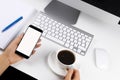 Woman hands holding the phone with isolated screen and cup of coffee. Business workplace with keyboard and business objects