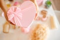 Woman hands holding pink colored heart shaped gift boxes of bath and body products for bridesmaids.