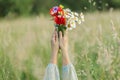 Woman hands holding poppy, daisy and cornflower bouquet in field in evening summer countryside, close up. Atmospheric moment. Royalty Free Stock Photo