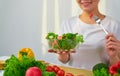 Woman hands holding salad bowl with eating tomato and various green leafy vegetables on the table at the home. Royalty Free Stock Photo