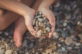 Woman hands holding small stones in hands on beach background with burning sun Royalty Free Stock Photo