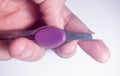 Woman hands holding tweezers with purple handle.