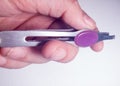 Woman hands holding tweezers with purple handle.