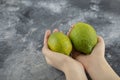 Woman hands holding two green fresh lemons