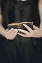 Woman hands holding vintage old book, very dark atmospheric sensual rural, gothic studio shot