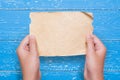 Woman hands holding vintage paper sheet over aged blue wooden ta Royalty Free Stock Photo