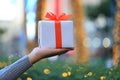 Woman hands holding white gift box with orange ribbon on bokeh a Royalty Free Stock Photo