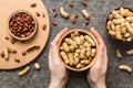 Woman hands holding a wooden bowl with close peanuts. Healthy food and snack. Vegetarian snacks of different nuts Royalty Free Stock Photo