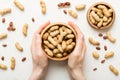 Woman hands holding a wooden bowl with close peanuts. Healthy food and snack. Vegetarian snacks of different nuts Royalty Free Stock Photo