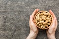 Woman hands holding a wooden bowl with close peanuts. Healthy food and snack. Vegetarian snacks of different nuts Royalty Free Stock Photo