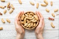 Woman hands holding a wooden bowl with close peanuts. Healthy food and snack. Vegetarian snacks of different nuts Royalty Free Stock Photo