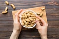 Woman hands holding a wooden bowl with close peanuts. Healthy food and snack. Vegetarian snacks of different nuts Royalty Free Stock Photo