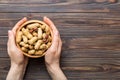 Woman hands holding a wooden bowl with close peanuts. Healthy food and snack. Vegetarian snacks of different nuts Royalty Free Stock Photo