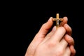 Woman hands holding wooden cross isolated on black