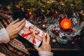 Woman hands holding xmas presents on a wooden table background. Merry Christmas and Happy New Year. golden ornaments, light candle Royalty Free Stock Photo