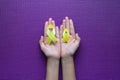 Woman hands holding yellow ribbon on purple background,Suicide prevention,Cancer disease awareness concept,Copy space for text