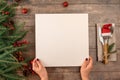 Woman hands holds menu in her hands while sitting at Christmas dinner table. Christmas tree decorations border on vintage wooden Royalty Free Stock Photo