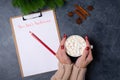 Woman hands holds mug with cacao, ready to write new year`s resolutions on blank list on dark background. Flat lay. Top Royalty Free Stock Photo