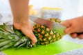 Woman hands with knife cutting pineapple top on cutting board Royalty Free Stock Photo