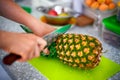 Woman hands with knife cutting pineapple top Royalty Free Stock Photo