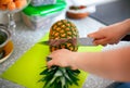 Woman hands with knife cutting pineapple top in domestic kitchen Royalty Free Stock Photo