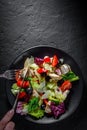 Woman hands with knife and fork eat Fresh salad with chicken breast, cheese, black olives,red pepper, lettuce, fresh sald leaves a Royalty Free Stock Photo