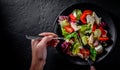 Woman hands with knife and fork eat Fresh salad with chicken breast, cheese, black olives,red pepper, lettuce, fresh sald leaves a Royalty Free Stock Photo