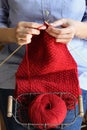 Woman hands knitting red scarf