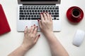 Woman hands on laptop keyboard with wireless mouse, cup of coffee, red notebook on white table Royalty Free Stock Photo