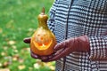 Woman hands in leather gloves holds a Halloween pumpkin outdoor in the autumn park