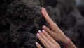 Woman hands with light-coloured manicure and nice missanga touching black stone