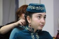 Woman hands making the tight braid of little girl dressed in national Crimean Tartar costume. Kyiv, Ukraine