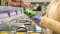 Woman hands in medical gloves chooses frozen spinach in package by opening the freezer in supermarket.Protective against Royalty Free Stock Photo