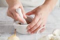 Woman hands with mortar with herbs on bright background