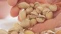 Woman hands opening pistachios above glass bowl