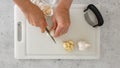 Woman hands peeling and cutting fresh garlic on a white plastic cutting board, view from above Royalty Free Stock Photo