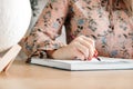 Woman hands with pencil, she is is writing in her notebook sitting at the table with book shelf background. Copy, empty space for Royalty Free Stock Photo