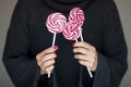 Woman hands with perfect nail polish holding some pink and white lollypops