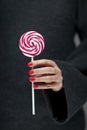 Woman hands with perfect nail polish holding some pink and white lollypops