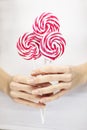 Woman hands with perfect nail polish holding some pink and white lollypops