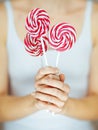 Woman hands with perfect nail polish holding some pink and white lollypops