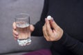 Woman hands with pills and glass of water. A young woman is taking medication, feeling bad. Healthcare concept