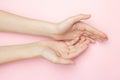 The woman hands on a pink background. Cosmetics for a sensitive skin care. Natural petal cosmetics, anti-wrinkle hand
