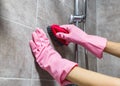 Woman hands in pink rubber gloves cleaning washing sink in bathroom. Close up. Disinfection of bath Royalty Free Stock Photo