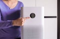 Woman hands pointing to screen of white modern air purifier in a living room for refresh air flow at home,Advanced air purifying a