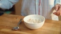 Woman hands pouring milk into cornflakes bowl. Woman eating cereal at home.