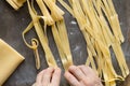 Woman hands prepare raw noodles for drying on powdered by flour wooden surface