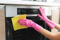 Woman hands in protective gloves cleaning oven with yellow rag in kitchen Royalty Free Stock Photo